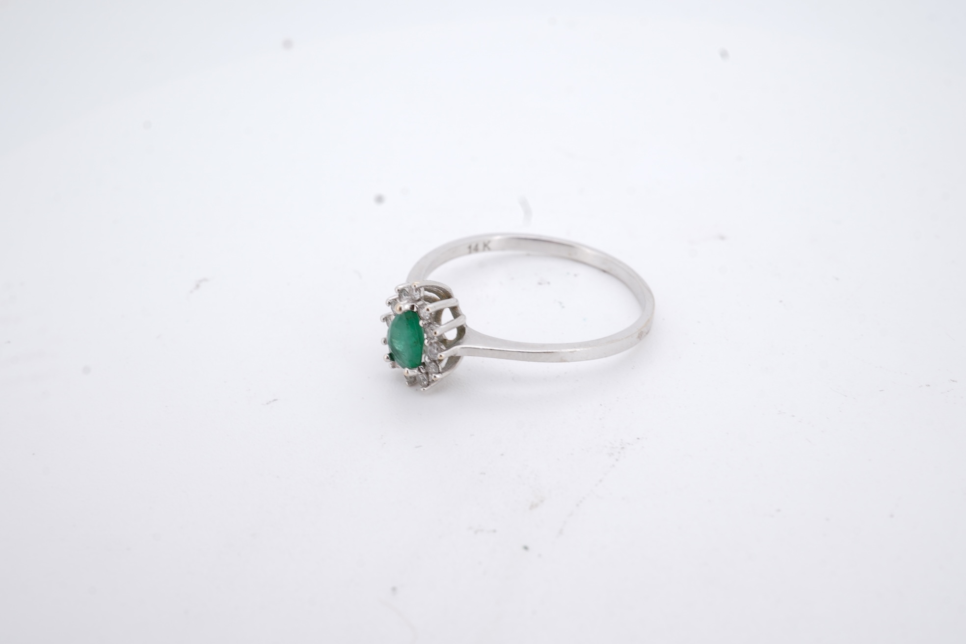 A modern white metal(stamped 14k), emerald and diamond set pear shaped cluster ring, size R, gross weight 1.3 grams.
